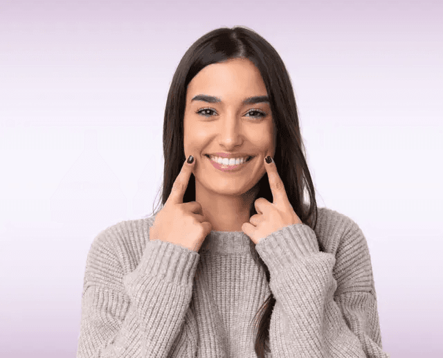 Smiling patient pointing to her healthy teeth after an oral cancer screening